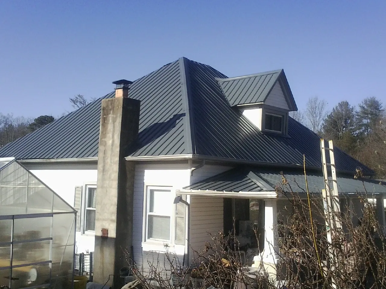 Dark blue standing seam metal roof on a white farmhouse with dormer — Slate & Tile Roof Repair by Roofing Brothers in Woodsboro