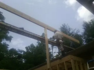 Carpenter setting a ridge beam over a new addition frame — Ice Dam Removal by Roofing Brothers in Woodsboro