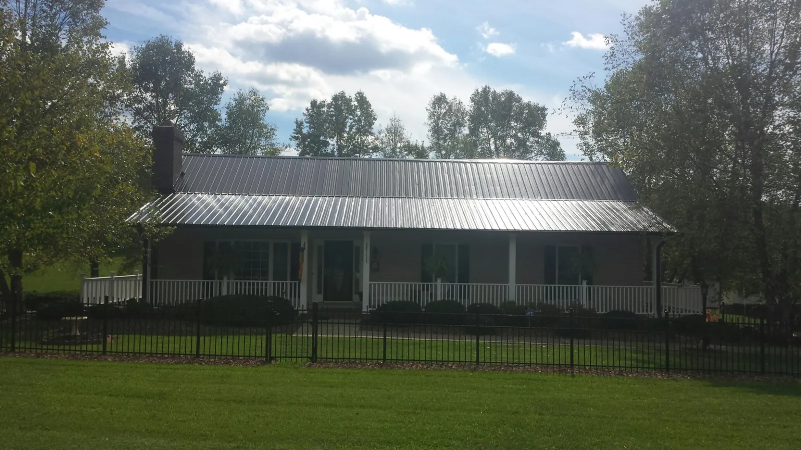 Gray metal roof on a brick ranch with a full width front porch — Gutter Guard Installation work by our crew in Woodsboro