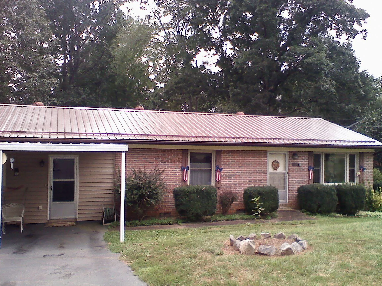 Bronze metal roof and carport on a brick ranch home — Roof Repair work by our crew in Woodsboro