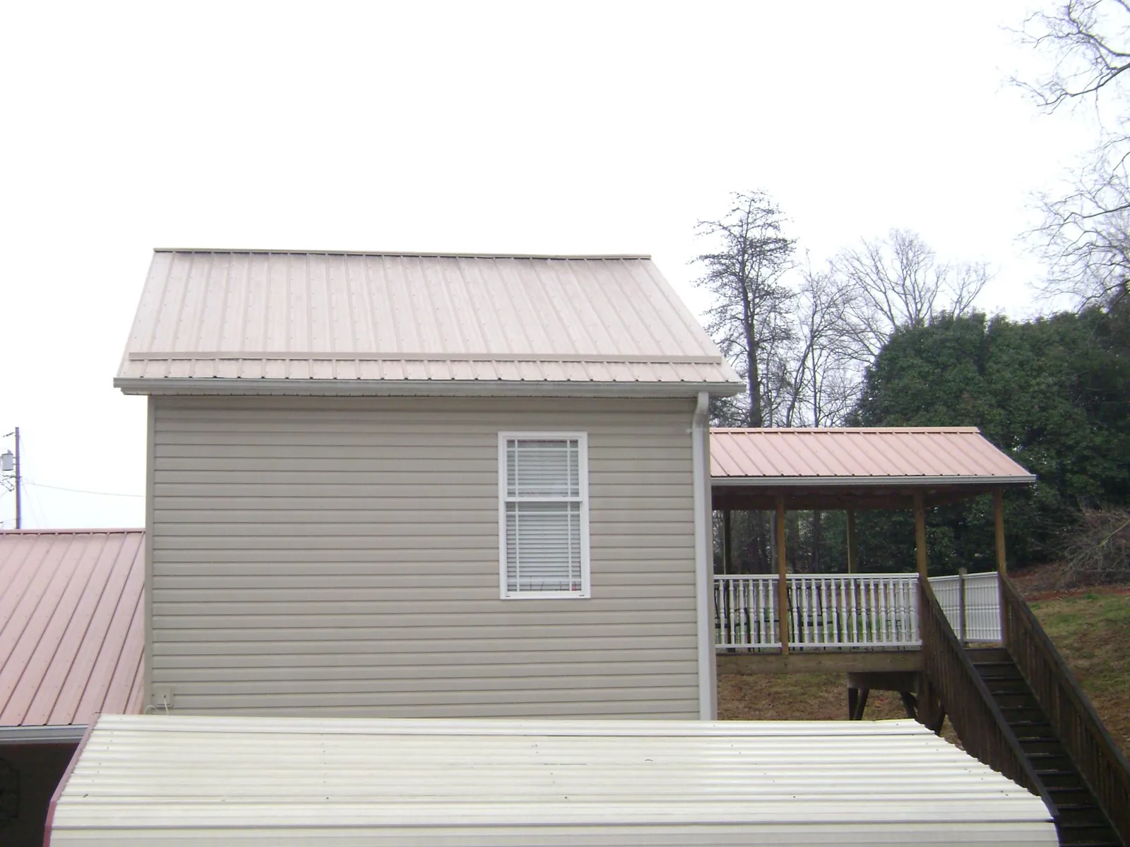 Tan metal roofs on a two story addition and attached porch, from a Roof Replacement job in Woodsboro