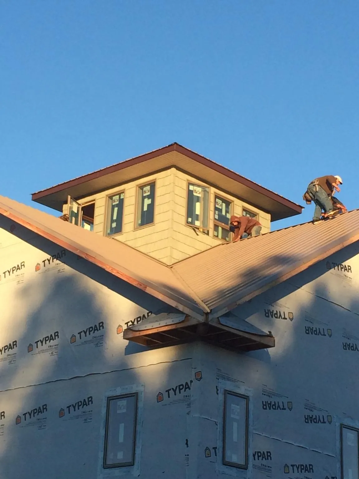 Roofers working around a rooftop cupola on a new metal roof at sunset — Roof Waterproofing in Woodsboro by Roofing Brothers
